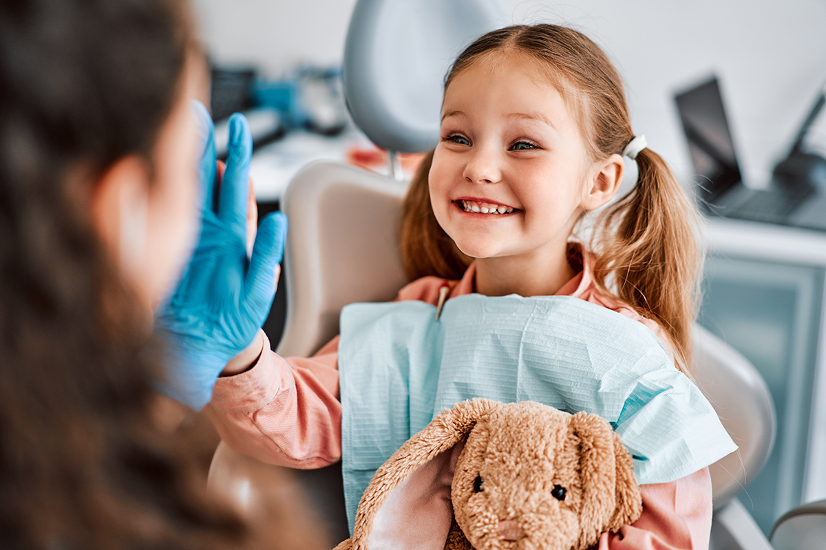 Young girl high-fiving her pediatric dentist after a checkup in Greenville, MS