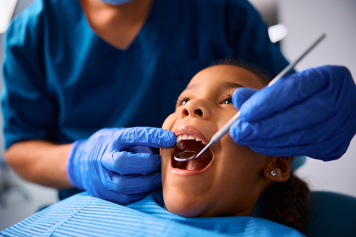 Pediatric dentist examining a child's teeth with modern digital tools
