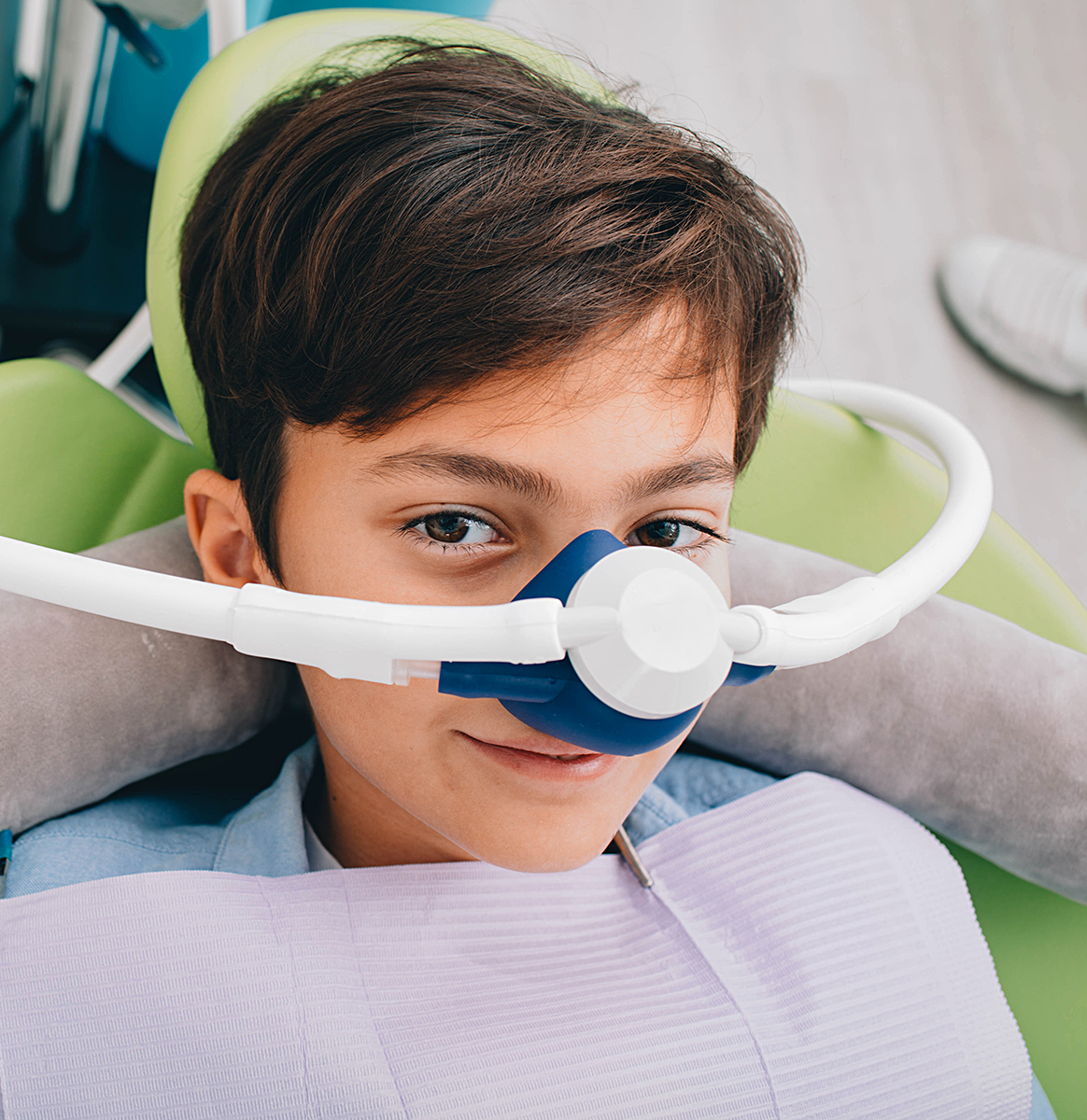 Young patient relaxed in the dental chair wearing a nitrous oxide mask during sedation